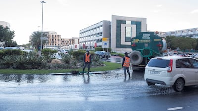 Municipality workers use a pump at a waterlogged road in Internet City on Sunday. Ruel Pableo for The National