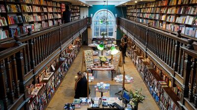 Customers wearing face covering browse for books inside the re-opened Daunt Books independent bookshop in London. AFP