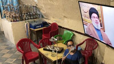 A man smokes a hookah as he watches Lebanon's Hezbollah leader Sayyed Hassan Nasrallah speak on television inside a coffee shop in the port city of Sidon, Lebanon July 12, 2019. Reuters