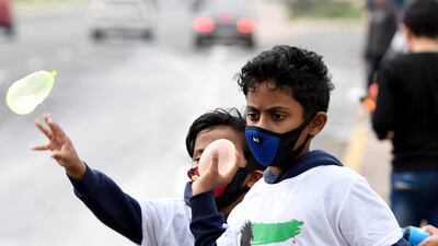 Kuwaiti children use protective masks as they play with water balloons during celebrations of the country's national day in the country's capital. EPA