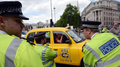Police officers look on during a protest by London black-cab drivers against Uber, a mobile phone app. Carl Court / AFP