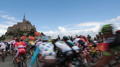 The pack rides at the start of the 188 km first stage of the 103rd edition of the Tour de France cycling race on July 2, 2016 between Mont-Saint-Michel (background) and Utah Beach Sainte-Marie-du-Mont, Normandy. AFP