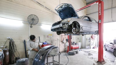 A man works on a car in Al Kashkha Auto Maintenance Garage in Sharjah. A new card system aims to regulate car maintenance at auto workshops. Victor Besa for The National