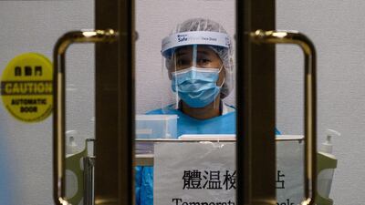 A medical worker wearing protective gear waits to take the temperature of people entering Princess Margaret Hospital in Hong Kong. AFP