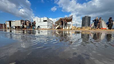 Displaced Palestinians gather as floodwater surrounds their tents at a camp in Khan Younis, southern Gaza. Reuters