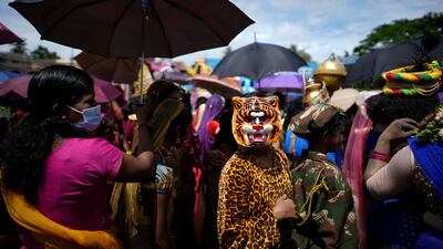 A woman holds an umbrella for children waiting to participate in the Athachamayam procession marking the beginning of the Onam festival in Kochi, Kerala, on August 30. AP