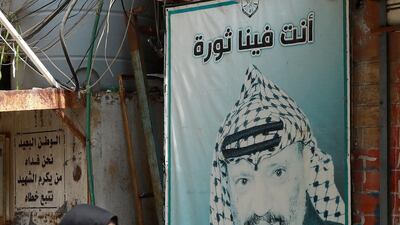 A refugee walks in front of a poster showing the late Palestinian leader Yasser Arafat in the camp Burj al-Barajneh, south of the capital Beirut. AFP