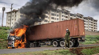 A Kenyan police officer stands next to a lorry set on fire in Nairobi during a protest against the cost-of-living crisis and last year's election results. AFP