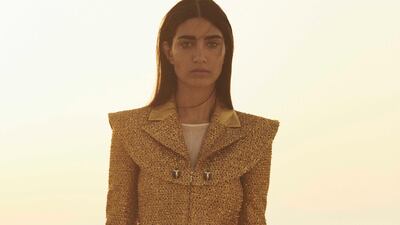 Gold dress in iridescent tweed; ecru dress in fine jersey (worn underneath); and black and gold hip pack in leather, chains and faux pearls, all from Chanel.