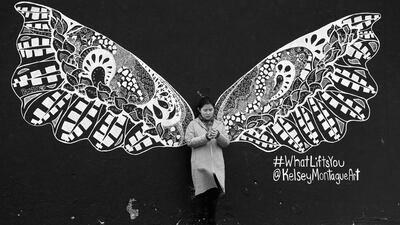 A visitor to Bondi Beach on a cold and wet day stops to take a selfie in front of a wall mural. Mark Kolbe / Getty Images