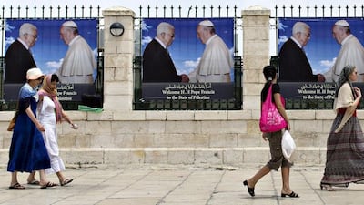 Tourists walk towards the Church of the Nativity, the accepted birthplace of Jesus Christ, in the West Bank town of Bethlehem on Wednesday, passing banners showing Pope Francis and the Palestinian president, Mahmoud Abbas. The Argentine-born pontiff will arrive in Bethlehem on May 24, 2014. Jim Hollander / EPA