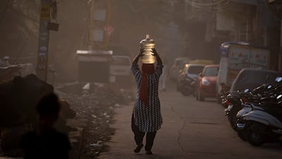A woman returns home after collecting drinking water from a tanker on World Water Day in New Delhi, India. Wednesday is the 30th anniversary of World Water Day. AP Photo