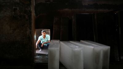 At a factory in New Delhi, a worker waits to load ice blocks on to a vehicle. Reuters