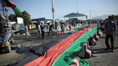 Afghans use a banner in the colours of the Afghan flag to cover victim's blood, after a deadly explosion struck a protest march by ethnic Hazaras, in Kabul, Afghanistan, Saturday, July 23, 2016. (AP Photos/Massoud Hossaini)