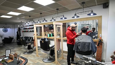 Barber Ben Fessey cuts the hair of his first customer after reopening his barber shop in Moreton, north west England. AFP