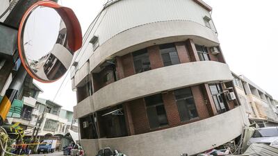 Crushed vehicles are seen under a building that was damaged after a powerful earthquake hit Tainan. Stringer / Reuters
