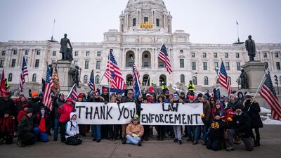 People pose with signs thanking law enforcement as Minnesota State troopers stand guard outside the Capitol during a rally supporting President Trump, January 9. AP