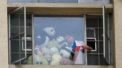 A girl waves a Philippine flag beside stuff toys as residents clap and sing from their windows to pay tribute to health workers, essential personnel and security forces during an enhanced community quarantine to prevent the spread of the new coronavirus in Manila, Philippines. AP