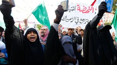 An Ennahda supporter ruling holds up a Quran as others shout slogans during a demonstration in Tunis on Saturday. Anis Mili / Reuters
