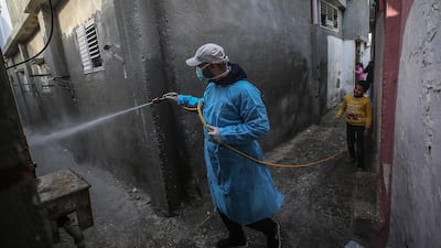 A Palestinian sprays disinfectant as a precaution against the spread of coronavirus, in the streets of the Al Nusairat refugee camp in the central Gaza Strip. EPA