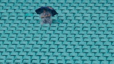 A solitary fan huddles under an umbrella as rain falls on the Sydney Cricket Ground delaying the start of the Women's T20 World Cup cricket semi-final matches in Sydney, on Thursday, March 5. AP