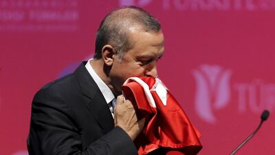 Turkey's president Recep Tayyip Erdogan kisses a handmade Turkish flag given to him as a gift from a Ugandan university student during a graduation ceremony in Ankara on June 11, 2015. Umit Bektas/Reuters