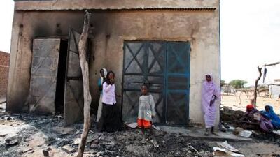Darfuri women and children stand in front of burnt shops in a marketplace in 2007.