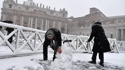 People build a snowman as it snows at St Peter's Square on February 26, 2018 at The Vatican. Tiziana Fabi / AFP