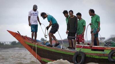 A diver, second from left, clings to a rubber hose that acts as primitive breathing device as he prepared to dive into the Yangon River in search of an ancient bell on August 15, 2014. The world’s largest copper bell, believed to have been lying deep beneath the riverbed for more than four centuries. Gemunu Amarasinghe/AP Photo