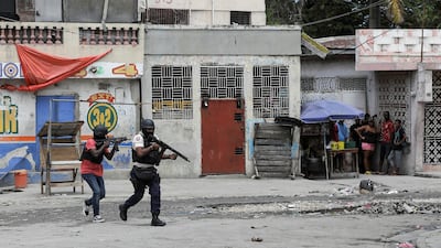 People huddle in a corner as police patrol the streets after gang members tried to attack a police station in Port-au-Prince, Haiti. Reuters