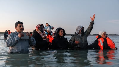 Traffickers hold people back as migrants wade into the water to get to a 'taxi boat' to take them across the channel, in Gravelines, France. Getty Images