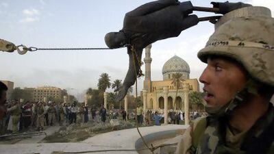 Iraqi civilians and US soldiers pull down a statue of Saddam Hussein in downtown Baghdad on April 9, 2003.