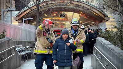 Emergency personnel escort a passenger from the 96th Street station, near the site of the derailment. AP