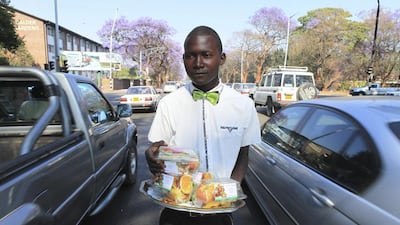 Kiziti Gezi, a street vendor, walking through cars as he sells neatly packed fruits to motorists in Harare, Zimbabwe. The once-prosperous southern African country is facing a high jobless rate, forcing many to flood the streets to hawk anything from medicines to car parts. Tsvangirayi Mukwazhi/AP Photo