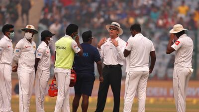 Officiating umpire Nigel Llong, third from right, speaks to Sri Lanka's players, wearing anti-pollution masks, as the game was briefly stopped during the second day of their third test cricket match in New Delhi. Altaf Qadri / AP Photo