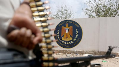 A Yemeni government soldier holds a weapon as he stands by an emblem of the STC at the headquarters of the separatist Southern Transitional Council in Ataq, Yemen August 27, 2019. Reuters