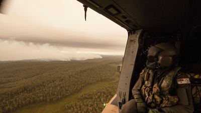 A Royal Australian Navy MRH-90 helicopter crew member looks out over fires burning near Cann River. The wildfires have so far scorched an area twice the size of the US state of Maryland. AP