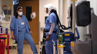 Hospital assistant Tracy Chambers, right, talks with another staff member in a hallway in the acute care unit of of Harborview Medical Centre, Seattle, where about half of the patients are Covid-19 positive or in quarantine after exposure, on Friday, January 14, 2022. AP