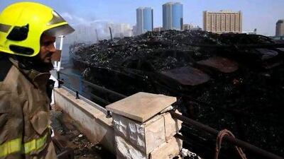 Dubai Civil Defence sprays water to the burnt cargo dhow at the Dubai Creek in Dubai.