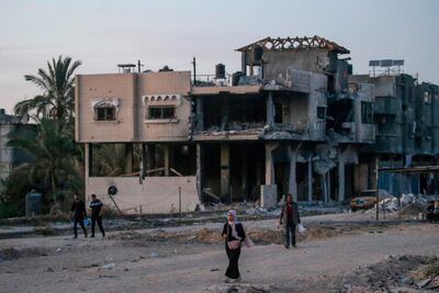 Internally displaced Palestinians walk next to destroyed buildings in Khan Younis town, southern Gaza Strip. EPA