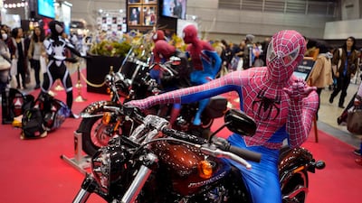 An attendee wearing a Spider-Man costume sits astride a motorbike. EPA