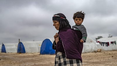 An elderly displaced Syrian woman carries a child in the Washukanni Camp for the internally displaced people near the predominantly Kurdish city of Hasakeh in northeastern Syria. AFP