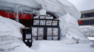 A restaurant underneath a pile of snow with only its drive-through sign visible. EPA