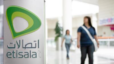People walk by an Etisalat sign inside a mall in Abu Dhabi. Galen Clarke / The National