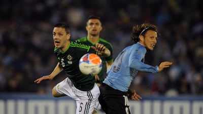Northern Ireland's defender Christopher Baird, left, vies for the ball with Uruguay's forward Diego Forlan during a friendly football match on May 30, 2014 at the Centenario Stadium, in Montevideo. AFP PHOTO / PABLO PORCIUNCULA