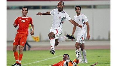 Sharjah's Abdullah Suhail, centre, hurdles an Ajman challenge during a pre-season friendly.