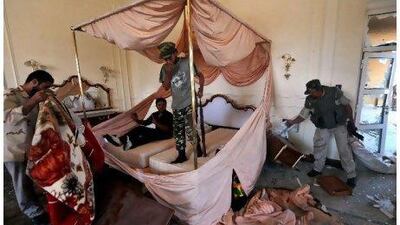 National Transitional Council fighters search a room at Muammar Qaddafi's Sirte palace yesterday. The council says it is near to claiming full control of the fugitive leader's hometown after seizing a convention centre that had served as a key base for his forces. Aris Messinis / AFP