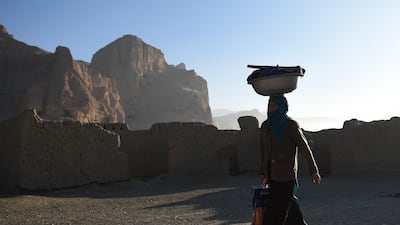 A Hazara woman carries a bucket on her head near the site of the Buddhas of Bamiyan statues in Bamiyan province. AFP
