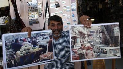 A 59-year-old Palestinian man who runs a stall in the old town of Hebron holding photos showing the market full of Palestinians in the early years following the 1967 Six-Day war. Hazem Bader / AFP