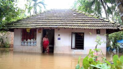 A woman stands at the door of her flooded home. EPA